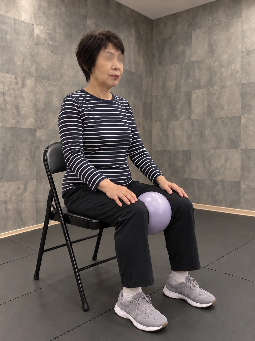 椅子に座ってラベンダー色のボールを膝で挟む女性